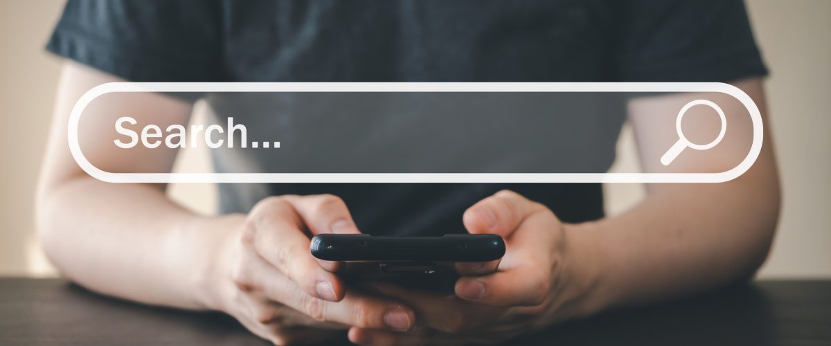 Man hand using mobile phone for searching and browsing internet information. Using search bar on website. Computer data technology, search engine optimization, and network concept.